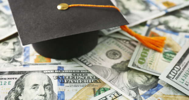 Close up view of graduation hat on dollar banknotes. Tuition fee