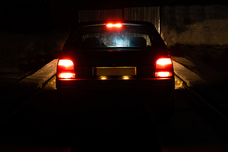 Red Light Of Parking Lights On A Car At Night. Closeup Of A Car
